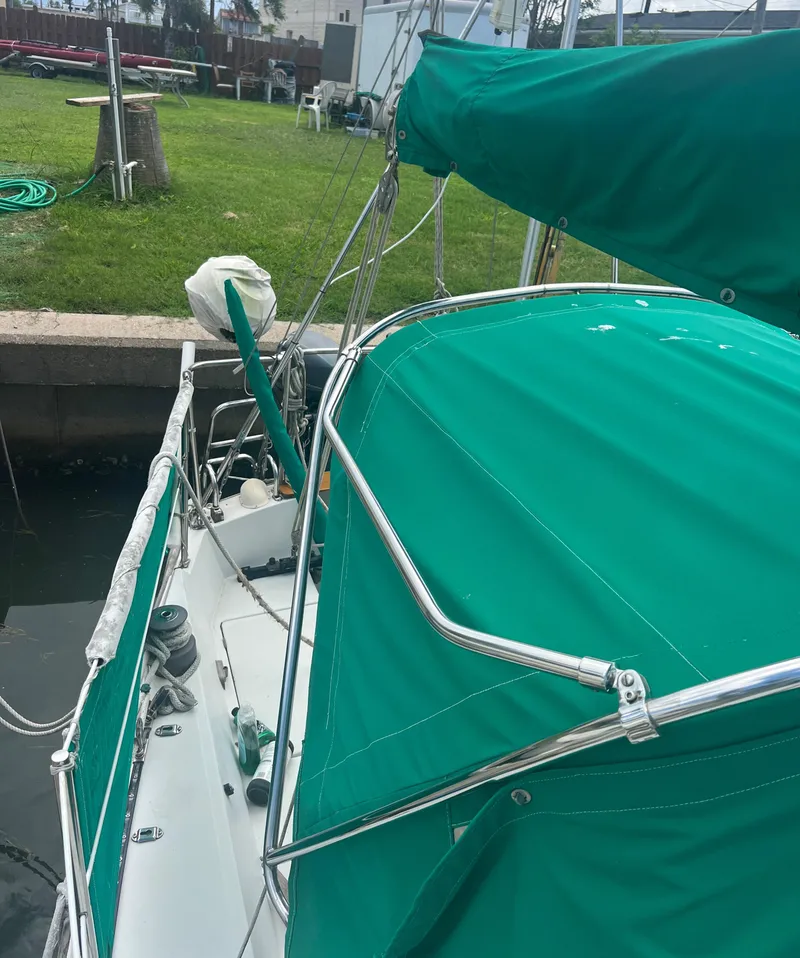 Slide: The Image of 1974 CAL T2 sailboat with green canopy docked near grassy area. - 7