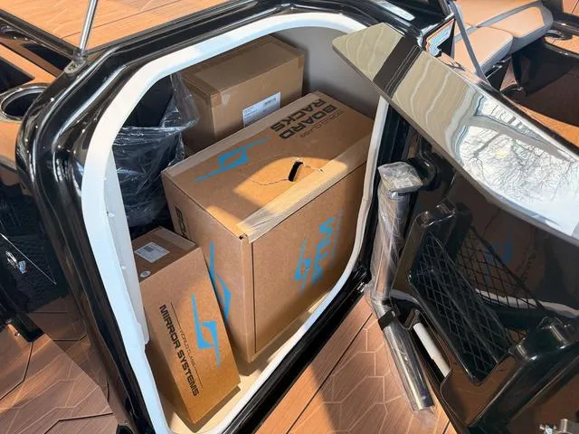 Slide: The Image of Storage compartment of 2025 Yamaha Boats 255XD filled with boxes and equipment. - 20