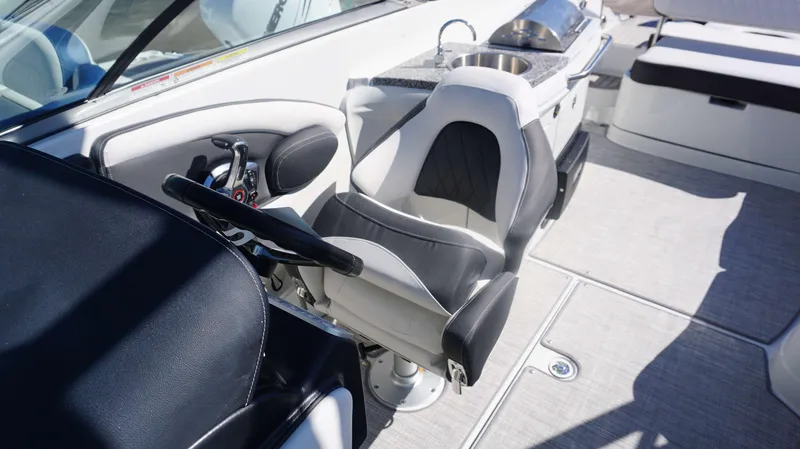 Slide: The Image of 2024 Crownline E 290 XS boat interior with helm seat, steering wheel, and sink. - 13
