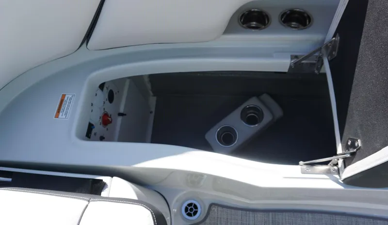 Slide: The Image of 2024 Crownline E 290 XS boat interior storage compartment with cup holders and control panel. - 7