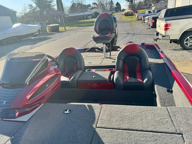 Slide: The Image of 2024 Vexus AVX1880 boat interior with red and black seats, parked outdoors. - 10