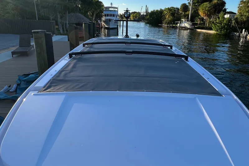 Slide: The Image of 2023 Axopar 37 Sun-Top docked by a serene waterfront. - 25