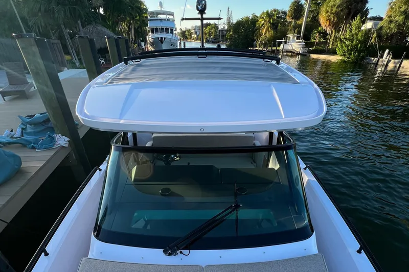 Slide: The Image of 2023 Axopar 37 Sun-Top boat docked by a scenic waterfront. - 26