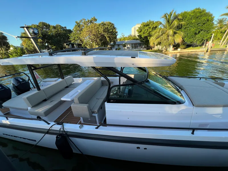 Slide: The Image of 2023 Axopar 37 Sun-Top boat docked near lush greenery and waterfront homes. - 6