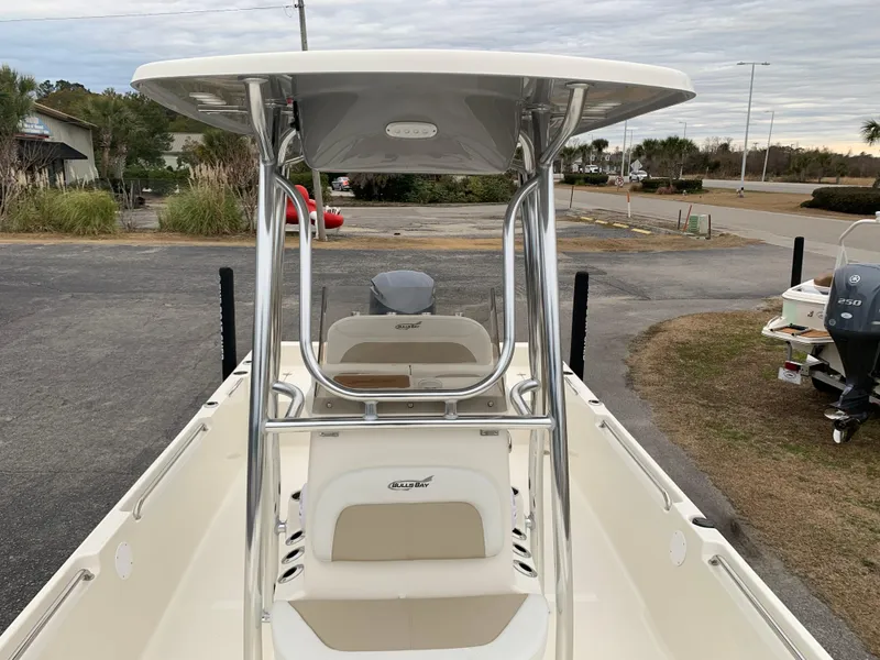Slide: The Image of 2025 Bulls Bay 2400 boat with T-top, parked on a trailer in a coastal area. - 25
