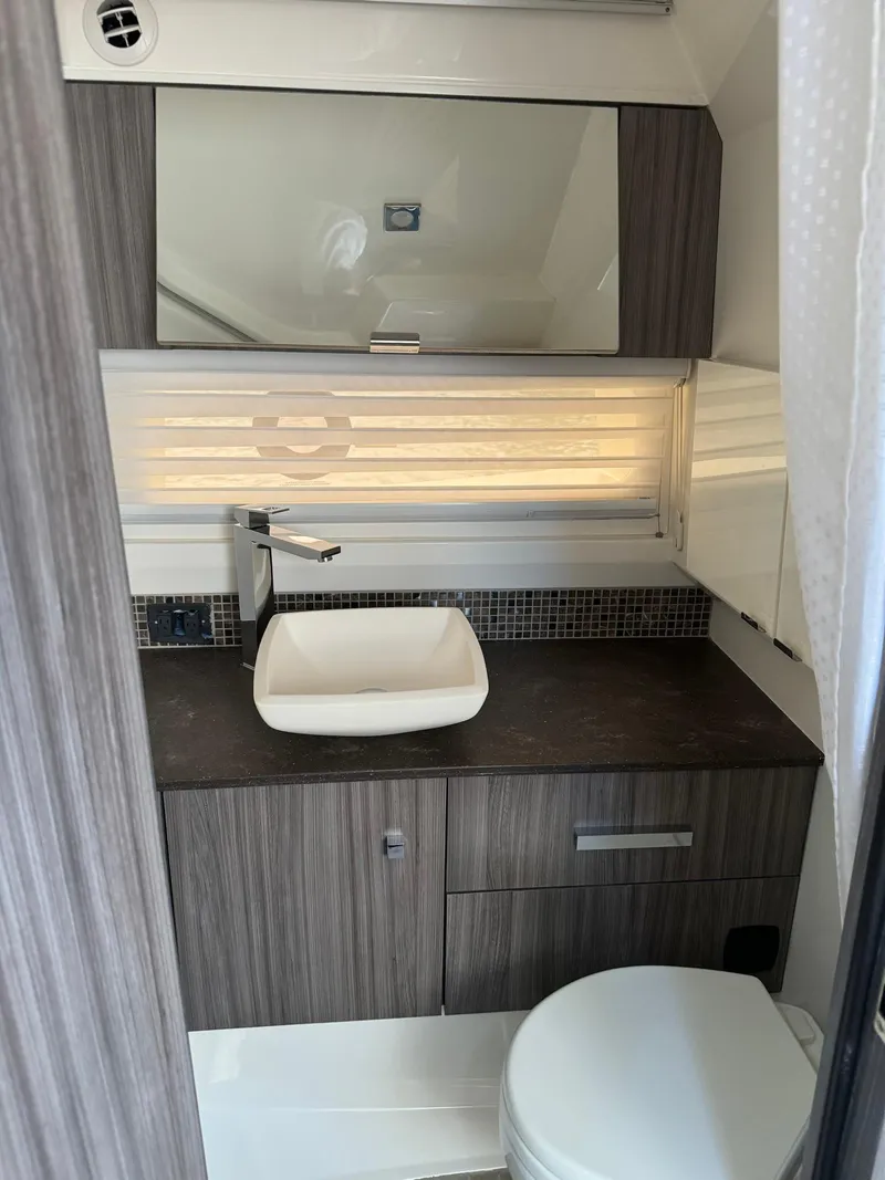Slide: The Image of 2021 Sea Ray 400 SLX OB boat bathroom with modern sink and wood cabinetry. - 12