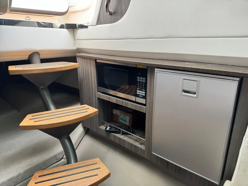 Slide: The Image of Interior of 2021 Sea Ray 400 SLX OB with microwave, mini-fridge, and wooden steps. - 16