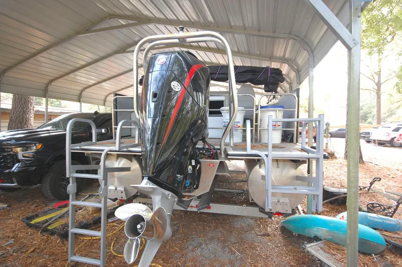Slide: The Image of 2021 Bentley Pontoons 243 Swingback under a metal canopy with an outboard motor. - 17