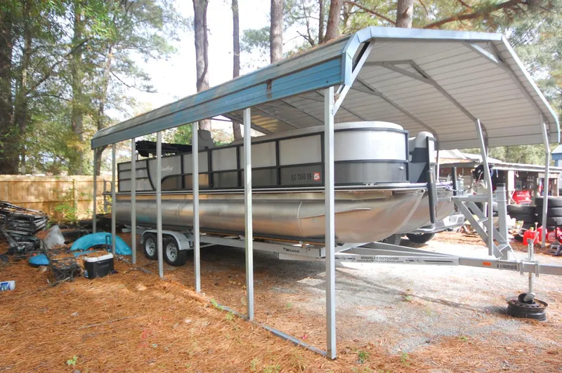 Slide: The Image of 2021 Bentley Pontoons 243 Swingback under a metal canopy in a wooded area. - 4