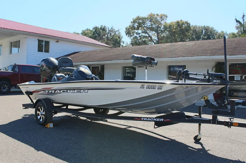 Slide: The Image of 2021 Tracker 195 TXW Tournament Edition fishing boat on trailer in front of building. - 3