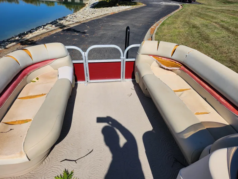Slide: The Image of 2012 Sun Tracker Party Barge 20 DLX with worn seating, parked near a lake. - 23
