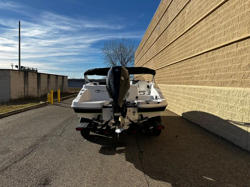 Slide: The Image of 2024 Tahoe 2150 boat parked beside a beige brick wall under a clear blue sky. - 3