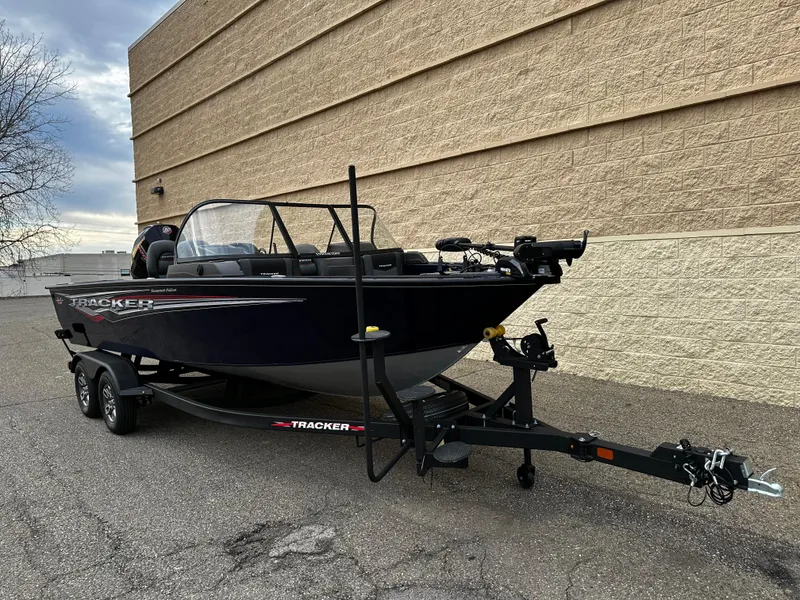 Slide: The Image of 2024 Tracker Targa V-19 WT boat on a trailer, parked beside a beige building. - 2
