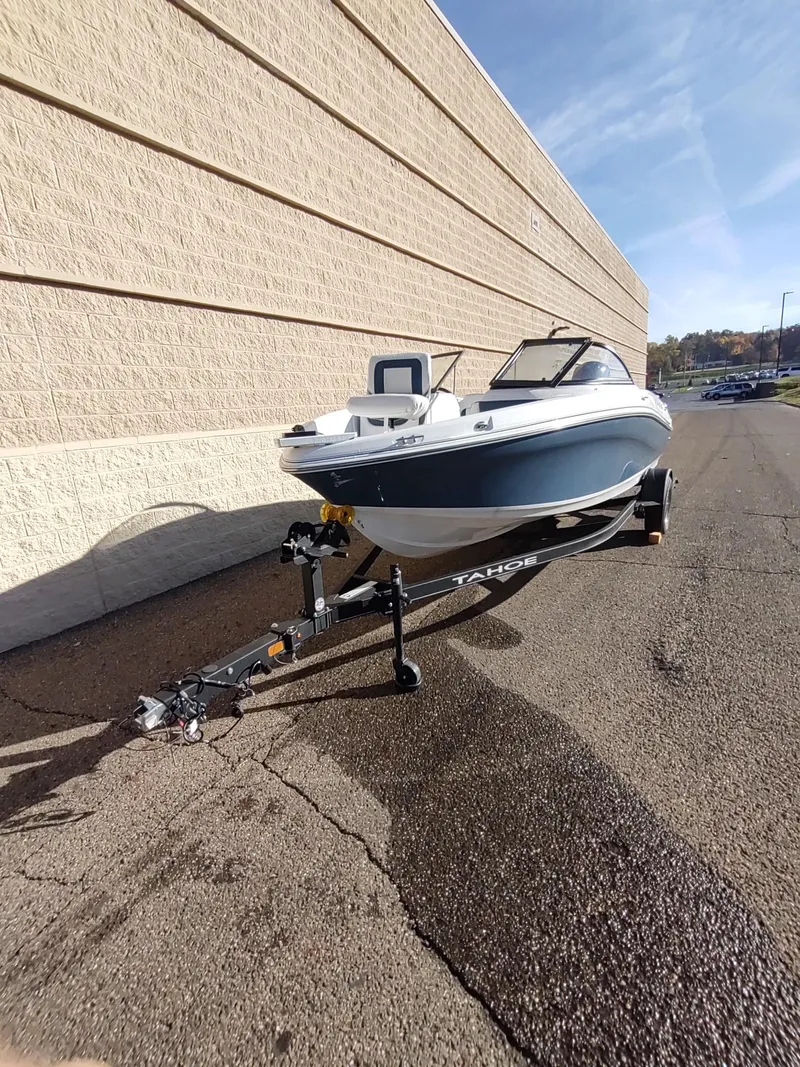 Slide: The Image of 2024 Tahoe 200 S boat on trailer, parked beside a beige building. - 6