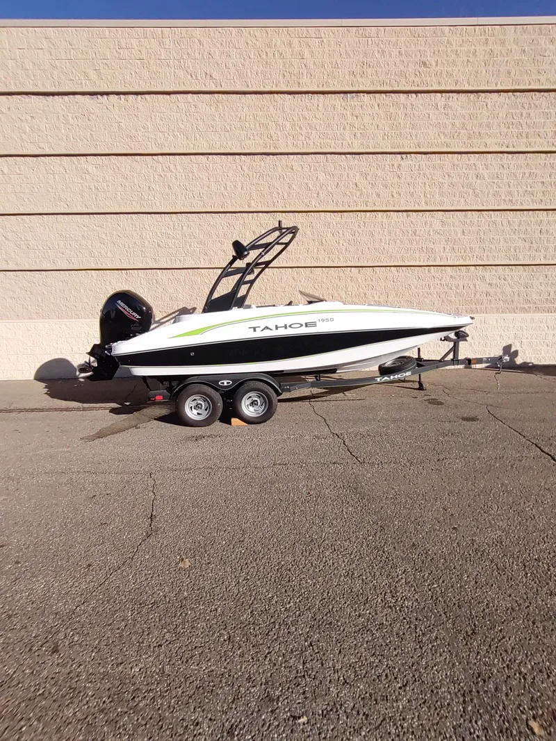Slide: The Image of 2024 Tahoe 1950 boat on trailer, parked against a beige wall. - 0