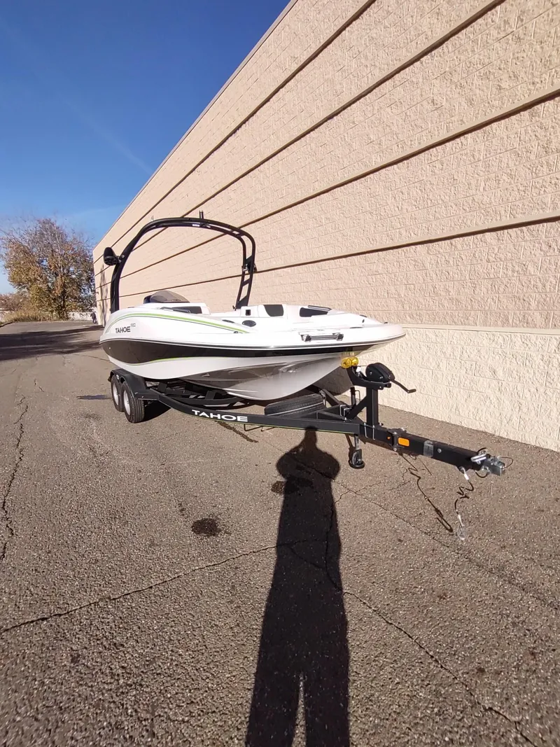Slide: The Image of 2024 Tahoe 1950 boat on trailer, parked beside a beige wall. - 2