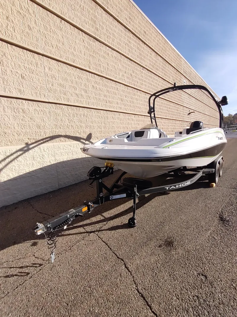 Slide: The Image of 2024 Tahoe 1950 boat on trailer, parked beside a beige wall. - 3