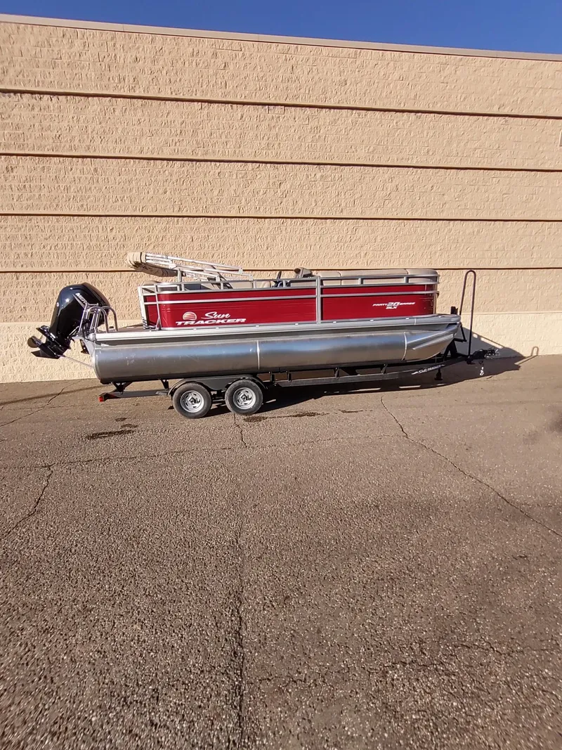 Slide: The Image of 2024 Sun Tracker Party Barge 20 DLX pontoon boat on trailer, red and silver design. - 2