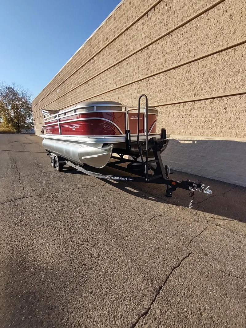 Slide: The Image of 2024 Sun Tracker Party Barge 20 DLX pontoon boat on trailer, parked by a wall. - 4