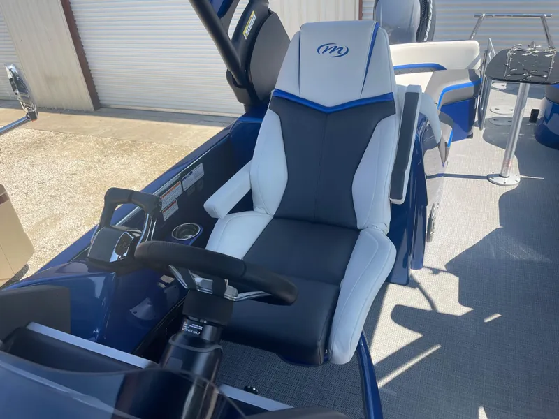 Slide: The Image of 2024 Manitou 25 XT SHP DE boat interior with captain's chair and steering wheel. - 6