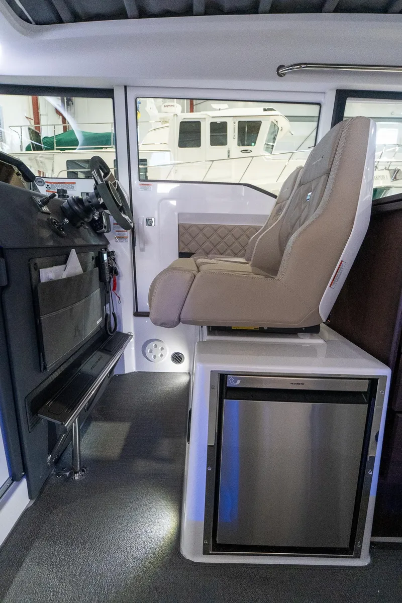 Slide: The Image of Interior of 2024 Axopar 37 Cross Cabin XC with captain's seat and mini fridge. - 24