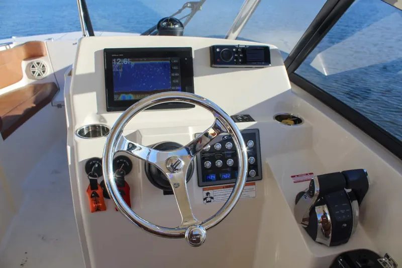 Slide: The Image of 2018 Scout 275 Dorado boat dashboard with steering wheel, navigation screen, and controls. - 23