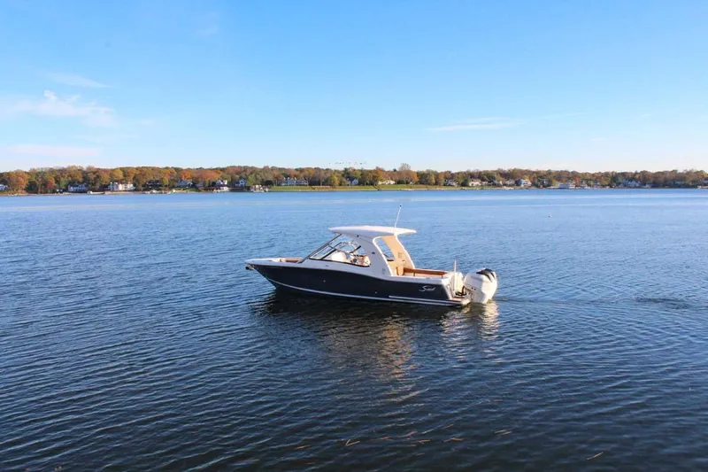 Slide: The Image of 2018 Scout 275 Dorado boat on a calm lake with a scenic shoreline. - 26