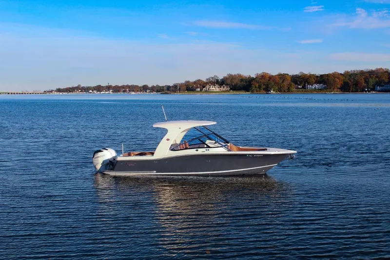 Slide: The Image of 2018 Scout 275 Dorado boat on calm water with scenic shoreline background. - 27