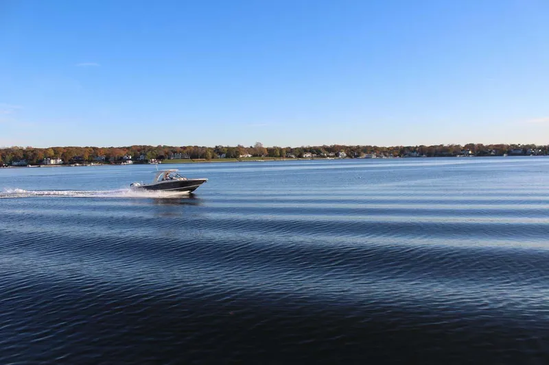 Slide: The Image of 2018 Scout 275 Dorado boat cruising on a calm lake under a clear blue sky. - 29