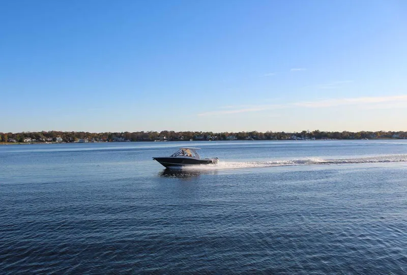 Slide: The Image of 2018 Scout 275 Dorado boat cruising on a calm lake under a clear blue sky. - 30