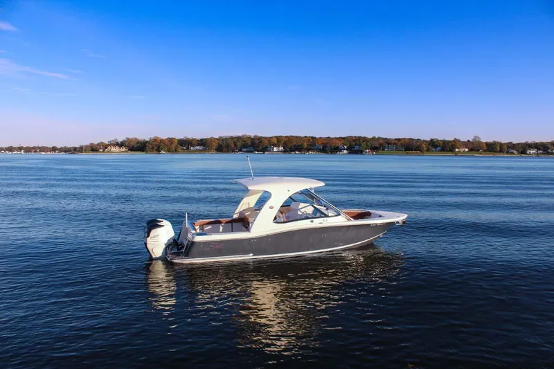 Slide: The Image of 2018 Scout 275 Dorado boat on calm water with scenic shoreline background. - 34
