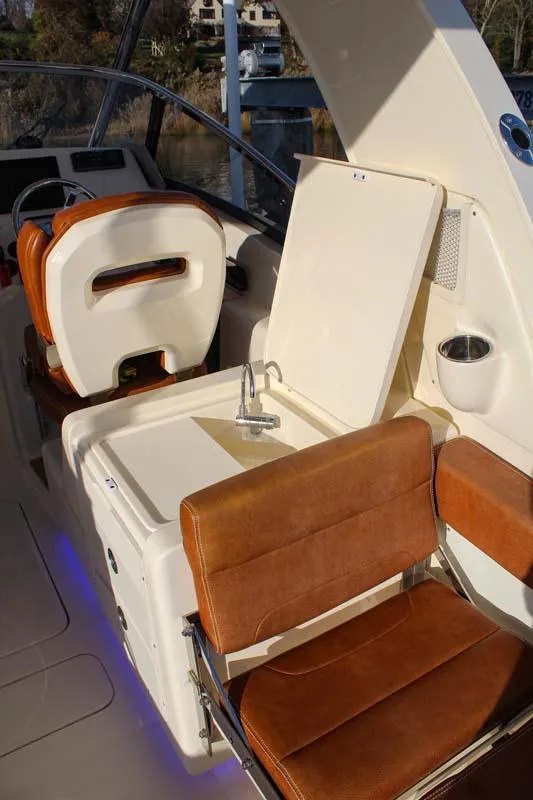 Slide: The Image of 2018 Scout 275 Dorado boat interior with tan leather seats and sink. - 8