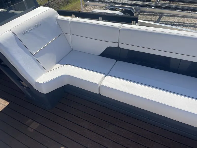 Slide: The Image of 2024 Manitou Explore 26 SHP boat with white cushioned seating and wooden deck. - 10
