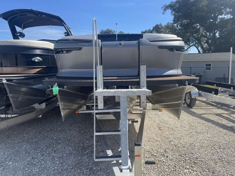 Slide: The Image of 2024 Manitou Explore 26 SHP pontoon boat on a trailer, ready for transport. - 11