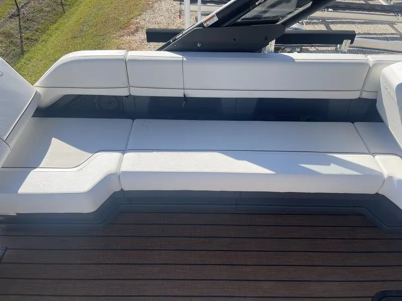 Slide: The Image of 2024 Manitou Explore 26 SHP boat with white cushioned seating and wooden deck. - 6