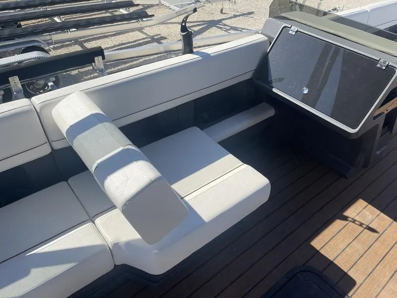 Slide: The Image of 2024 Manitou Explore 26 SHP boat interior with white seating and wooden flooring. - 8