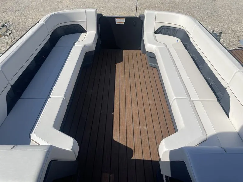 Slide: The Image of 2024 Manitou Explore 26 SHP boat interior with spacious seating and wooden flooring. - 9