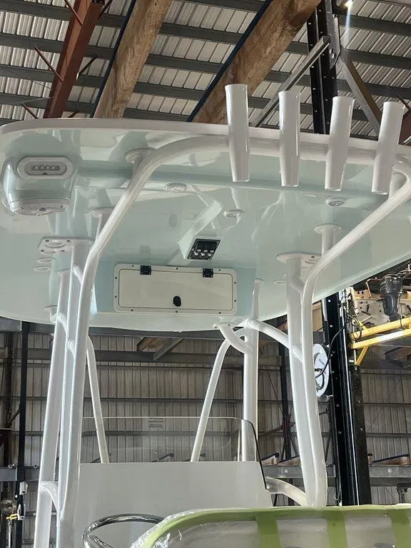 Slide: The Image of 2024 BlackJack 256 Bay boat T-top with rod holders in a warehouse setting. - 14