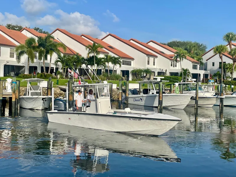 Slide: The Image of Rambo 27 boat (2019) on calm water near waterfront homes with red roofs and palm trees. - 20