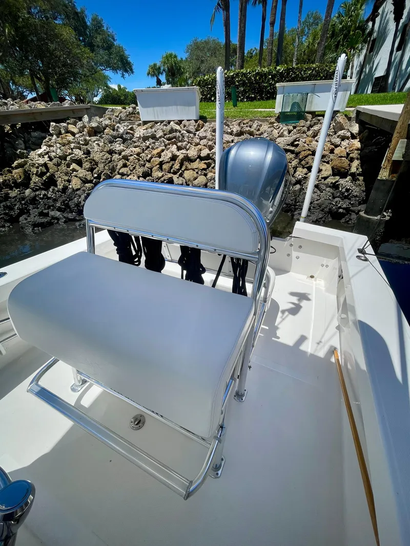 Slide: The Image of 2019 Rambo 27 boat with white seating and outboard motor, docked near rocky shore. - 4