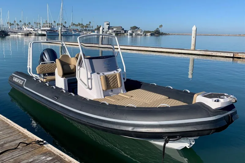 The Image of 2024 Highfield SP660 boat docked at a marina with calm waters and sailboats in the background. - 1