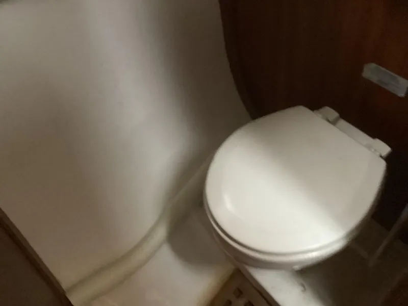 Slide: The Image of 1993 Ellis Downeast Hardtop boat bathroom with white toilet and wooden paneling. - 18