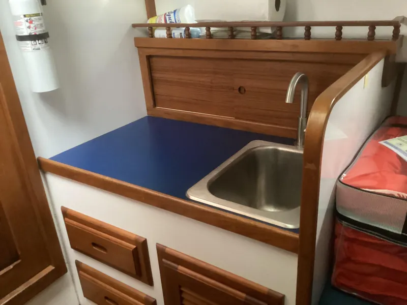 Slide: The Image of 1993 Ellis Downeast Hardtop boat kitchenette with sink and wooden cabinets. - 20