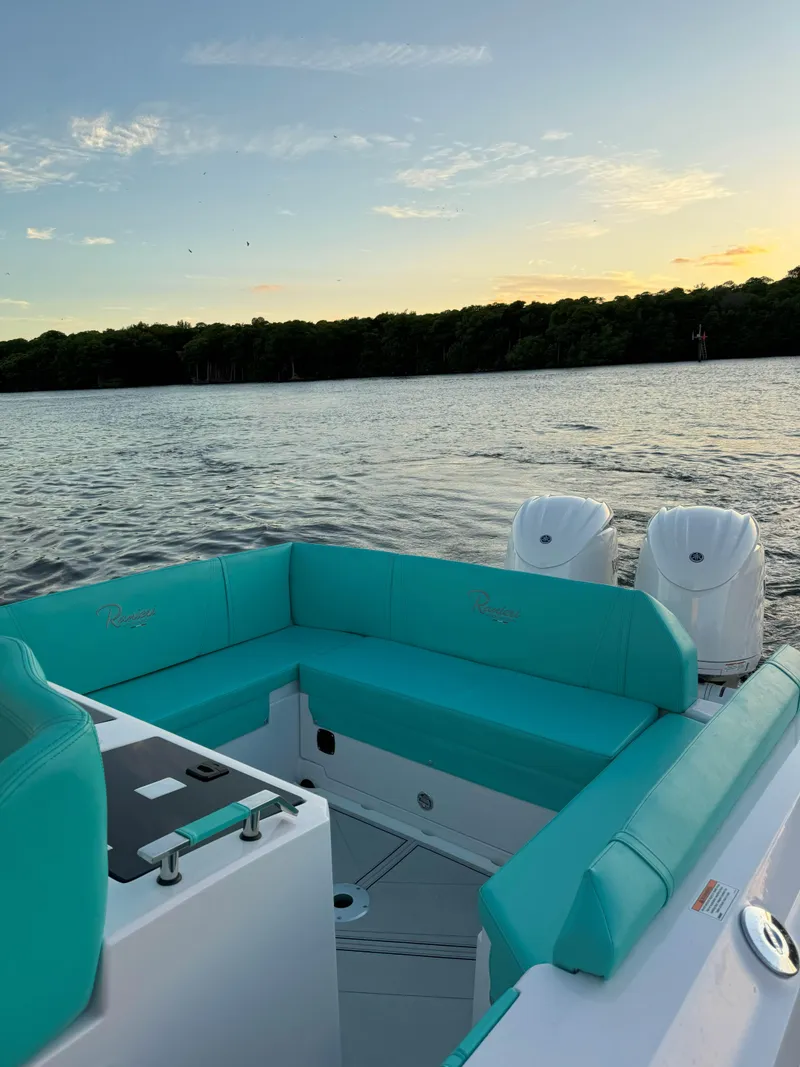 Slide: The Image of 2025 Ranieri CAYMAN 27.0 SPORT TOURING boat with turquoise seating on a serene lake at sunset. - 26