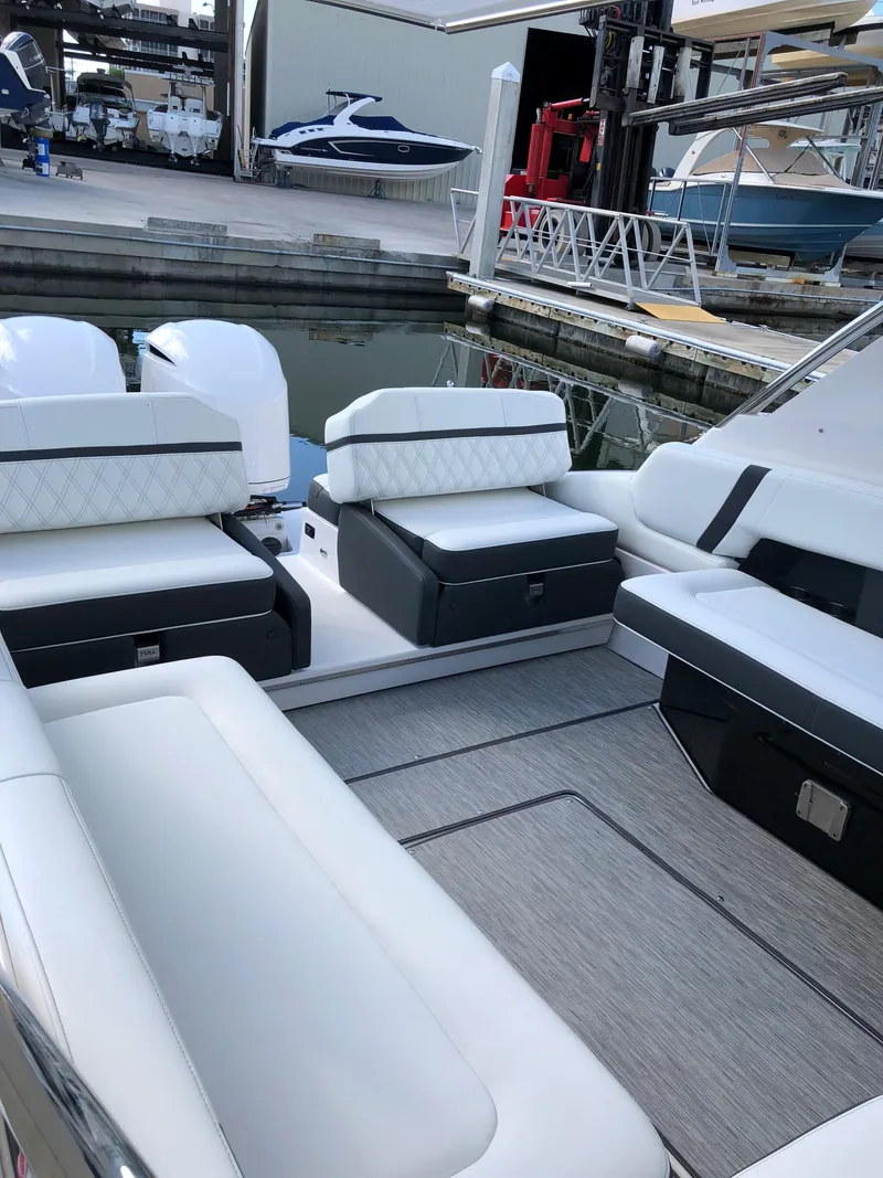 Slide: The Image of 2019 Regal 29 OBX boat interior with white seating at a marina. - 3