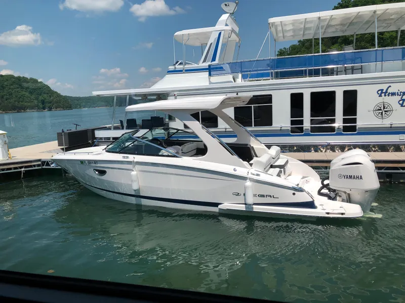 Slide: The Image of 2019 Regal 29 OBX boat docked near a large yacht on a sunny day. - 5