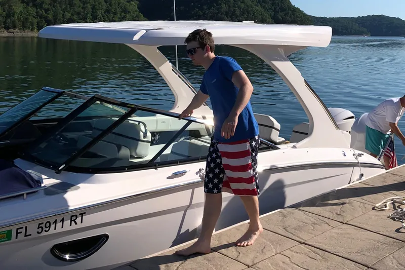 Slide: The Image of Man boarding a 2019 Regal 29 OBX boat docked by a lake. - 8