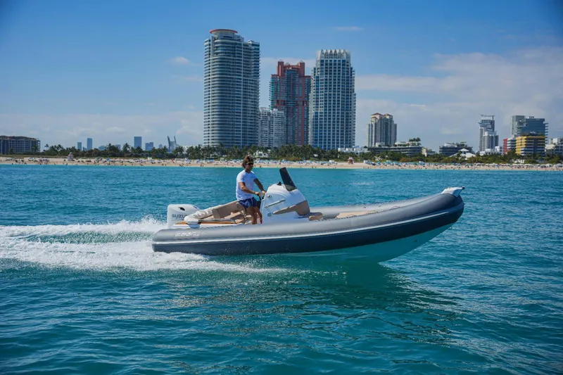 The Image of Man driving 2023 2 Bar 6.20 boat on blue ocean near city skyline. - 0