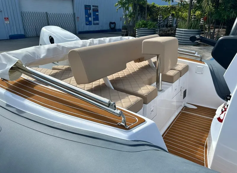 Slide: The Image of Luxury seating area on 2023 2 Bar 6.20 boat with tan cushions and teak flooring. - 14
