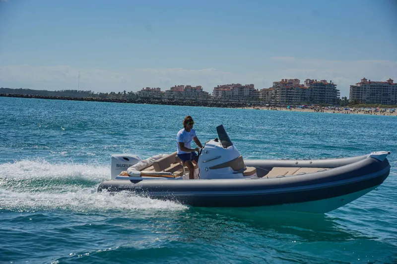 Slide: The Image of Person driving a 2023 2 Bar 6.20 boat on the ocean near a coastal city. - 2